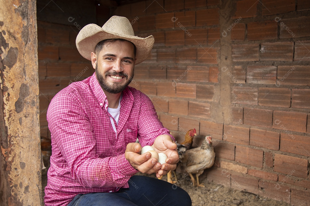 Homem jovem agricultor sobre galinheiro segurando ovos de galinha