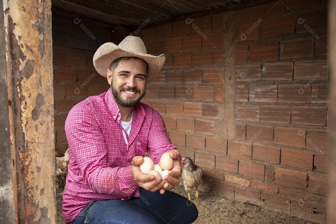 Homem jovem agricultor sobre galinheiro segurando ovos de galinha