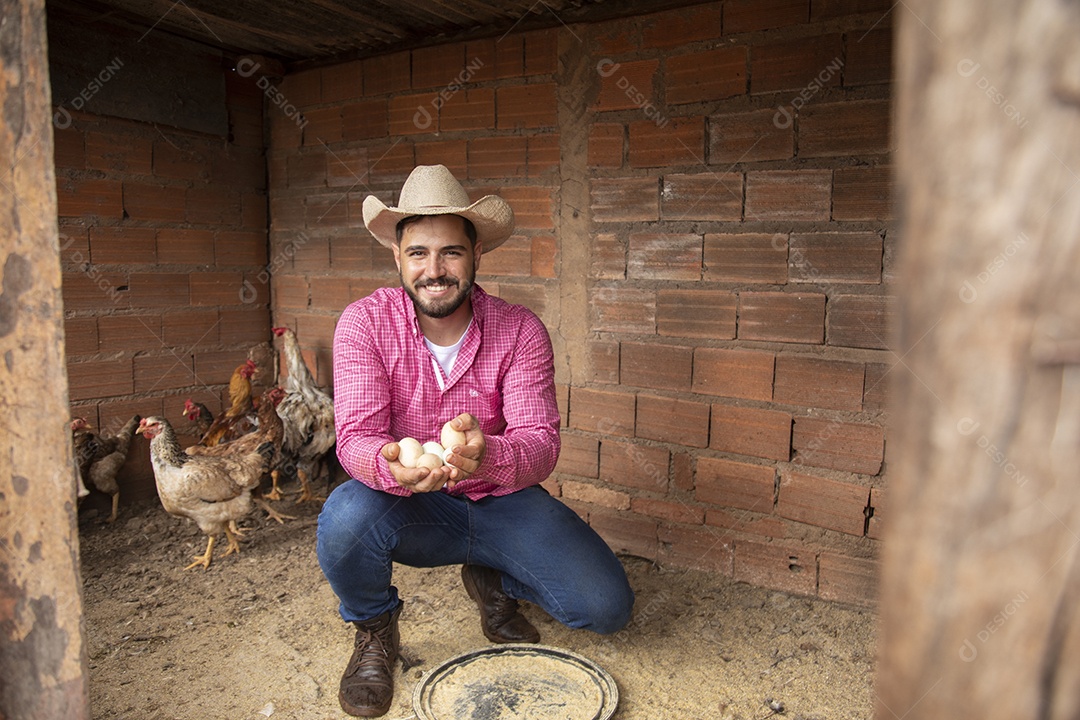 Homem jovem agricultor sobre galinheiro segurando ovos de galinha