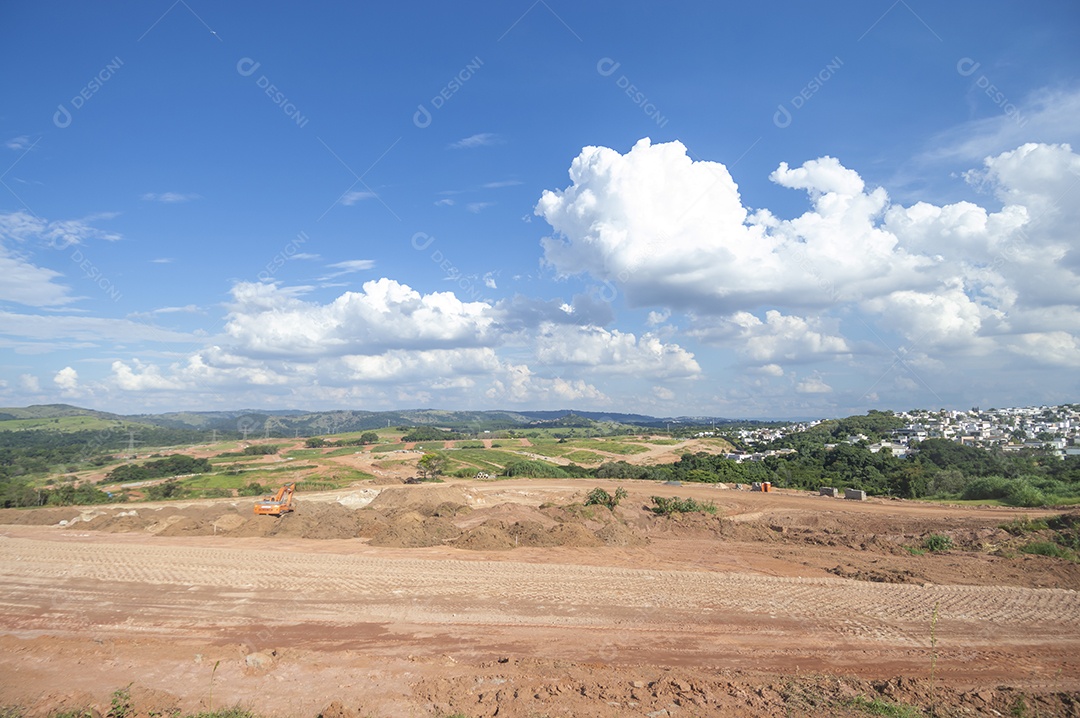 Paisagem mostrando caminhões e tratores no início de uma construção que se tornará uma área urbana e deixará de ser uma paisagem de vegetação.