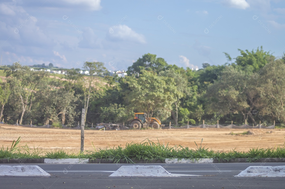 Paisagem mostrando caminhões e tratores no início de uma construção que se tornará uma área urbana e deixará de ser uma paisagem de vegetação.