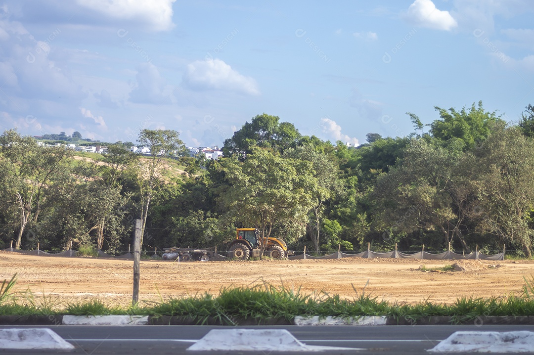 Paisagem mostrando caminhões e tratores no início de uma construção que se tornará uma área urbana e deixará de ser uma paisagem de vegetação.