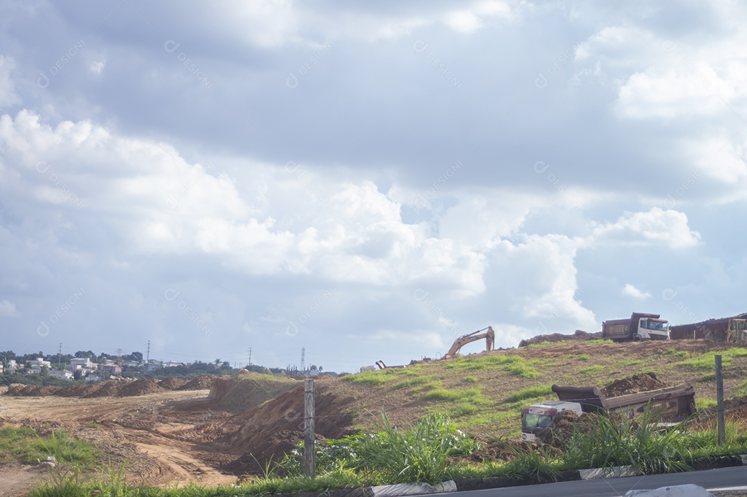 Paisagem mostrando caminhões e tratores no início de uma construção que se tornará uma área urbana e deixará de ser uma paisagem de vegetação.