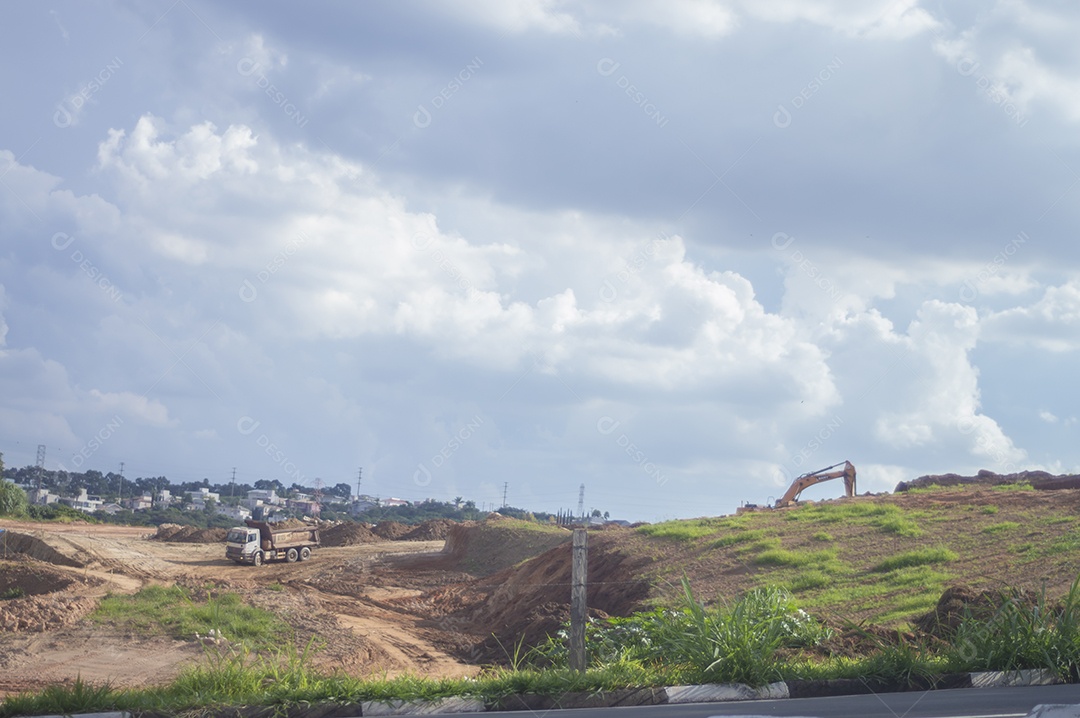 Paisagem mostrando caminhões e tratores no início de uma construção que se tornará uma área urbana e deixará de ser uma paisagem de vegetação.
