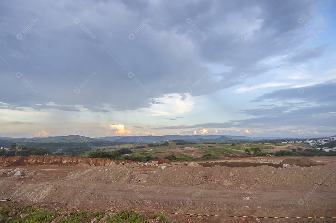 Paisagem mostrando caminhões e tratores no início de uma construção que se tornará uma área urbana e deixará de ser uma paisagem de vegetação.