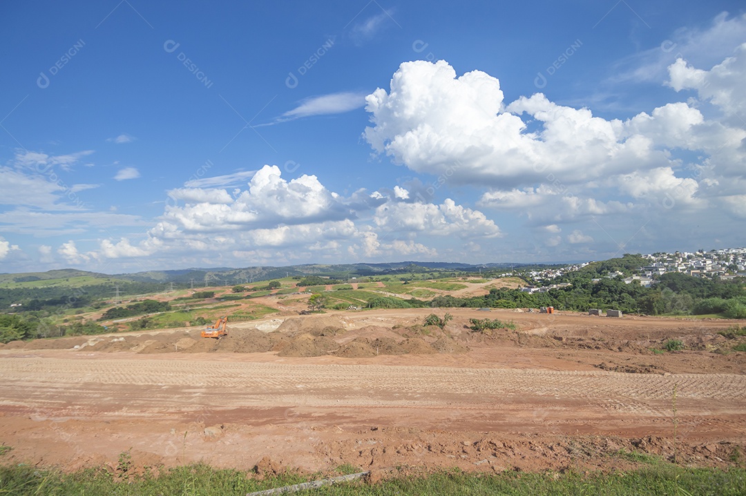 Paisagem mostrando caminhões e tratores no início de uma construção que se tornará uma área urbana e deixará de ser uma paisagem de vegetação.