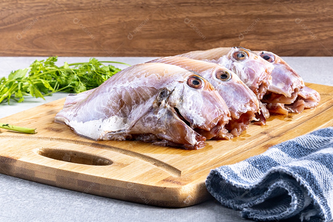 Peixe peroa limpo na tábua de madeira e coentros, pronto a fritar.