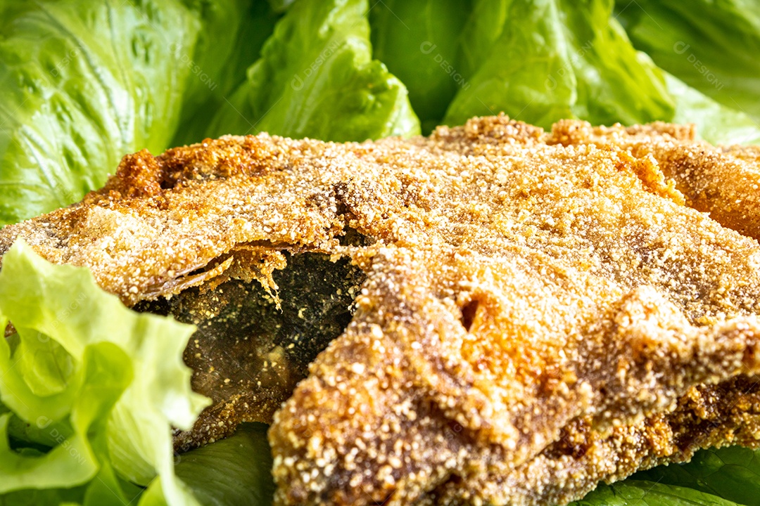 Peixe peroa limpo na tábua de madeira e coentros, pronto a fritar.