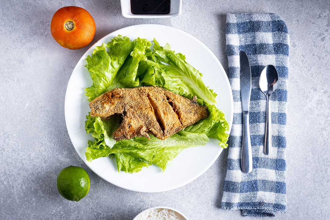Peixe peroa limpo na tábua de madeira e coentros, pronto a fritar.