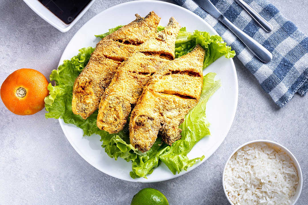 Peixe peroa limpo na tábua de madeira e coentros, pronto a fritar.