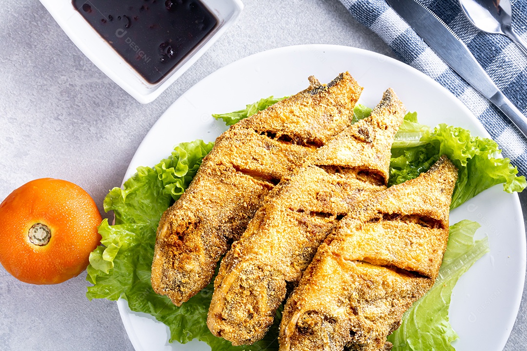 Peixe peroa limpo na tábua de madeira e coentros, pronto a fritar.