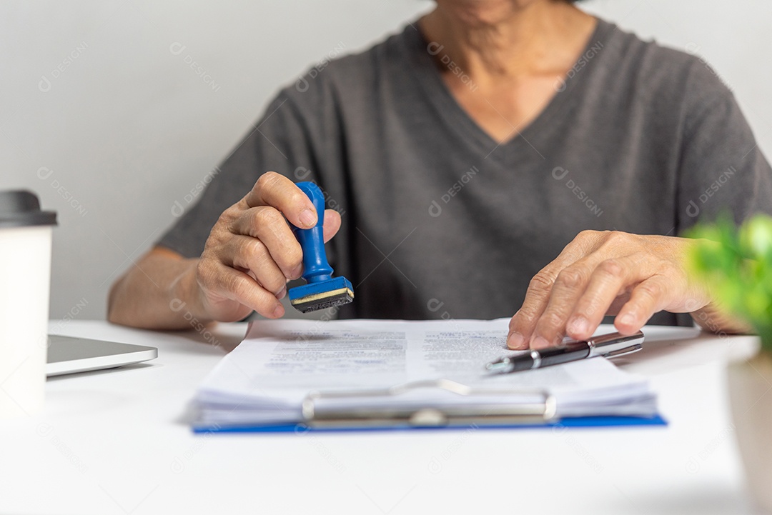 Mulher carimbando a aprovação de documentos bancários de finanças de trabalho ou de marketing de investimento