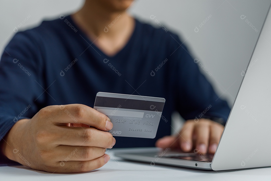 Mão de homem segurando cartão de crédito e usando laptop. Empresário ou empresário trabalhando