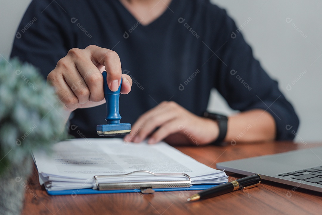 Homem carimbando aprovação de documentos bancários de financiamento de trabalho ou de marketing de investimento em contrato de documento certificado no escritório na mesa.