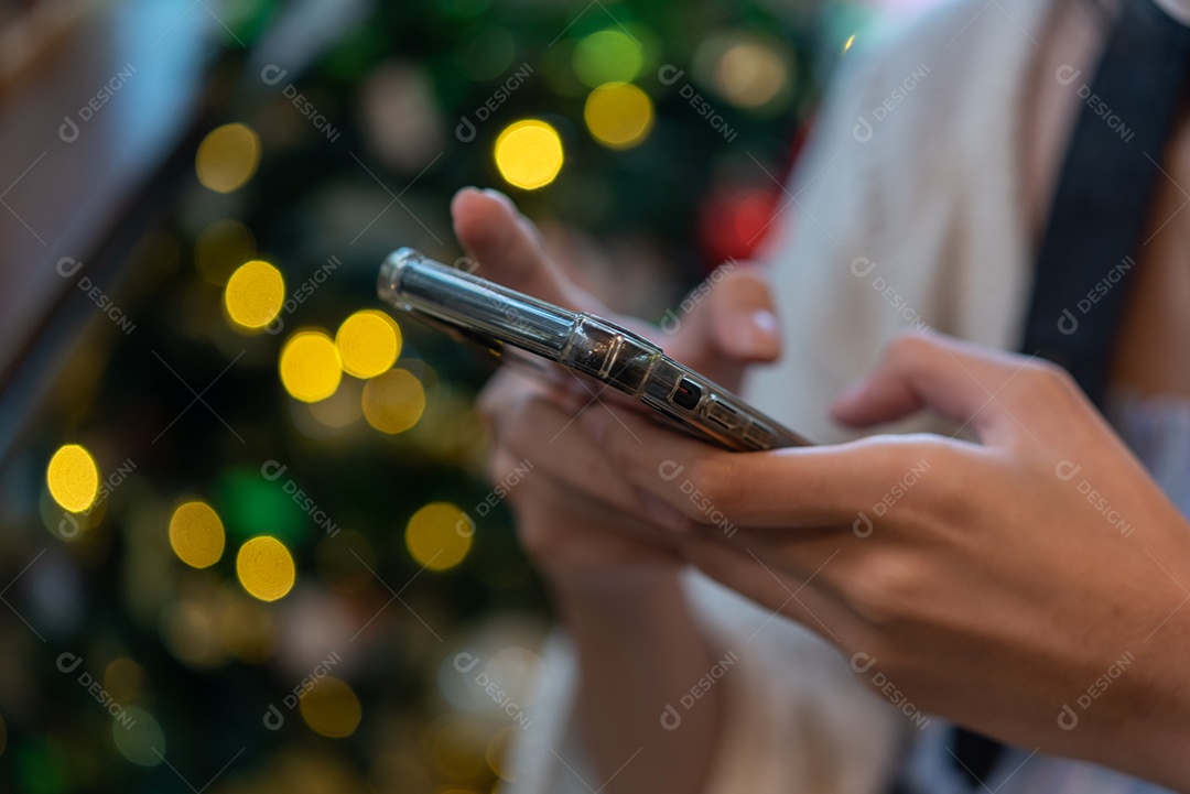 Mulher segurando tecnologia digital de smartphone móvel em fundo bokeh.