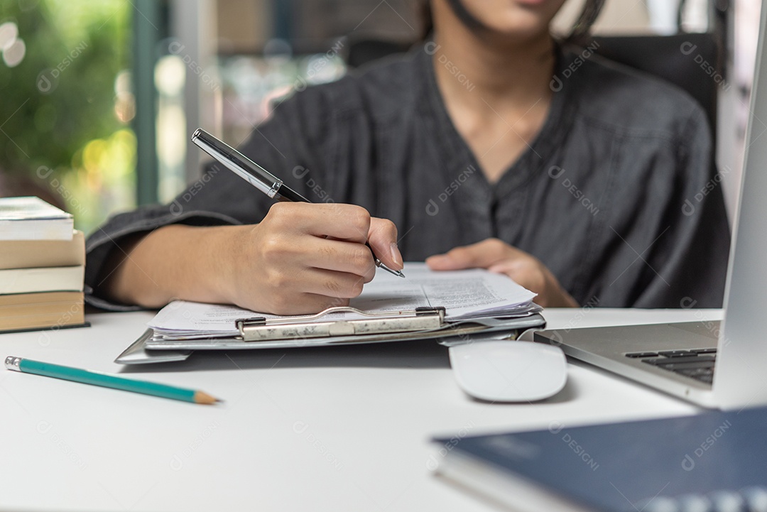 mão de uma mulher com caneta escrevendo contrato de assinatura no documento na área de transferência.