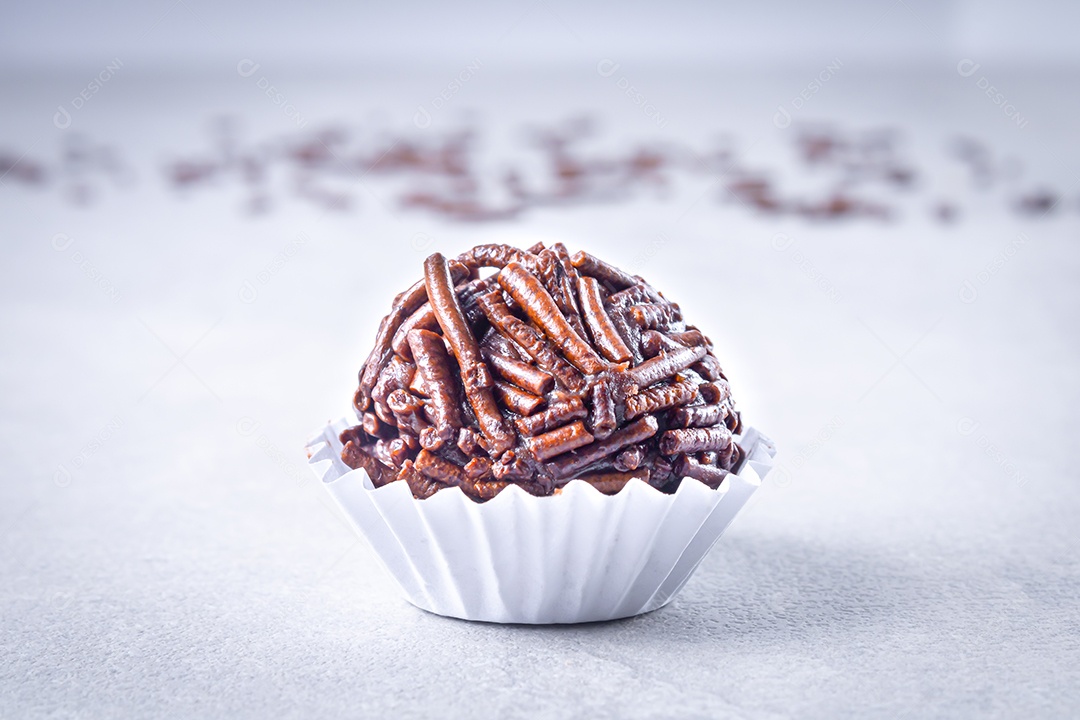 Brigadeiro em forma branca sobre fundo branco com chocolate granulado.