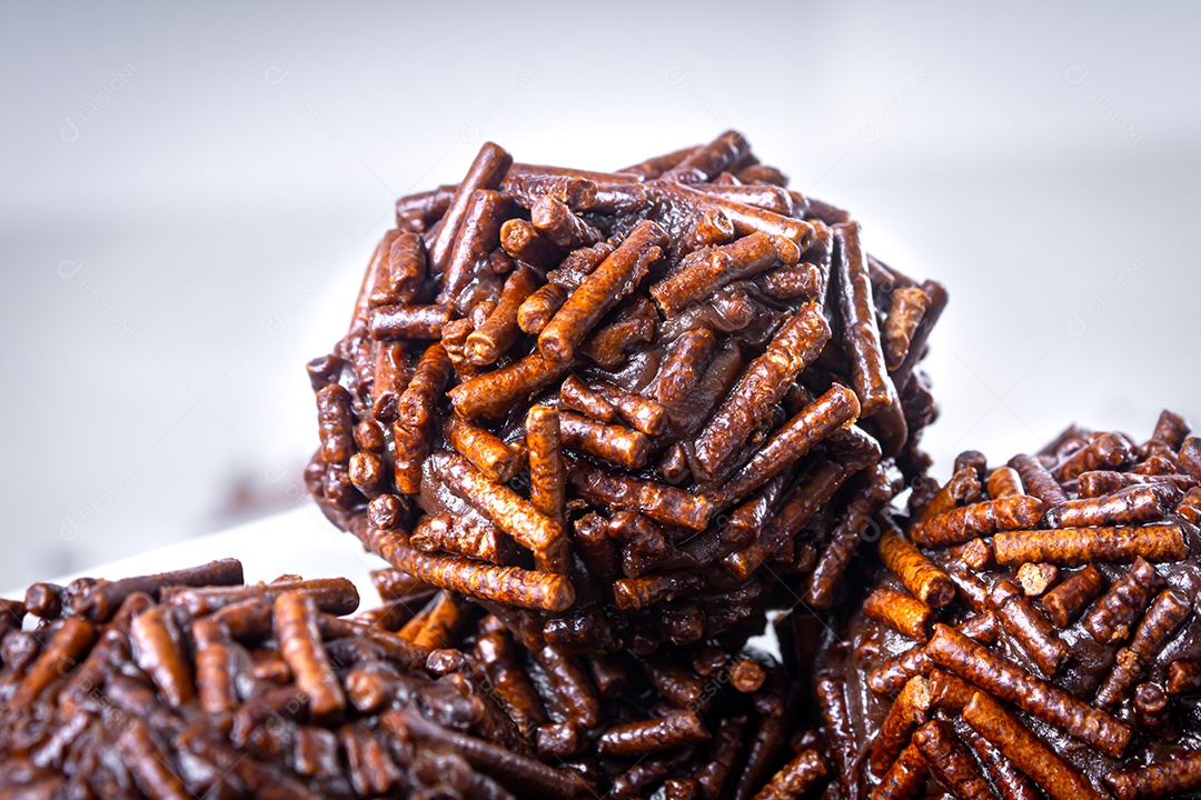 Vários doces brigadeiro em tigela branca. Fundo de mesa branco.