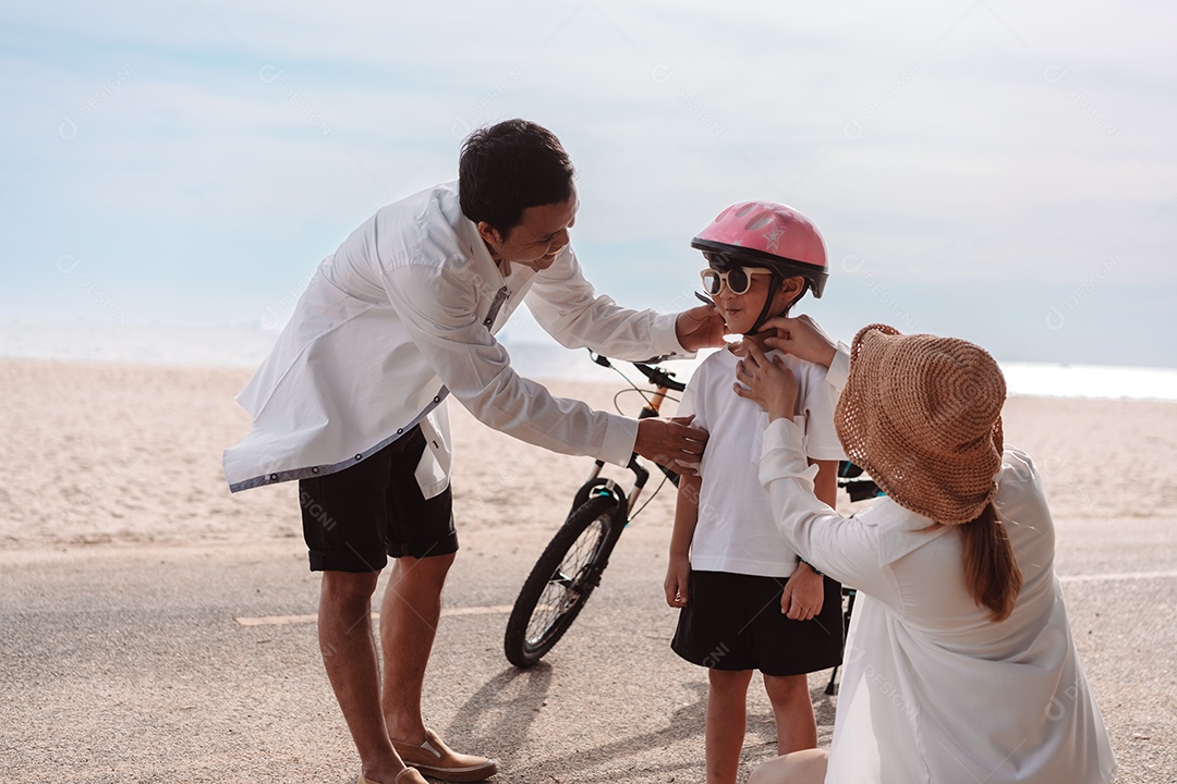 Família passeando pela praia ensinando filho a andar de bicicleta