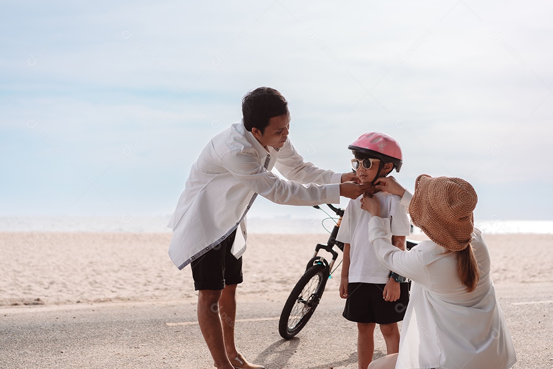 Família passeando pela praia ensinando filho a andar de bicicleta