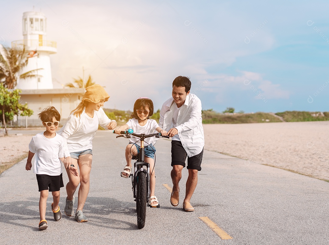 Família passeando pela praia ensinando filho a andar de bicicleta