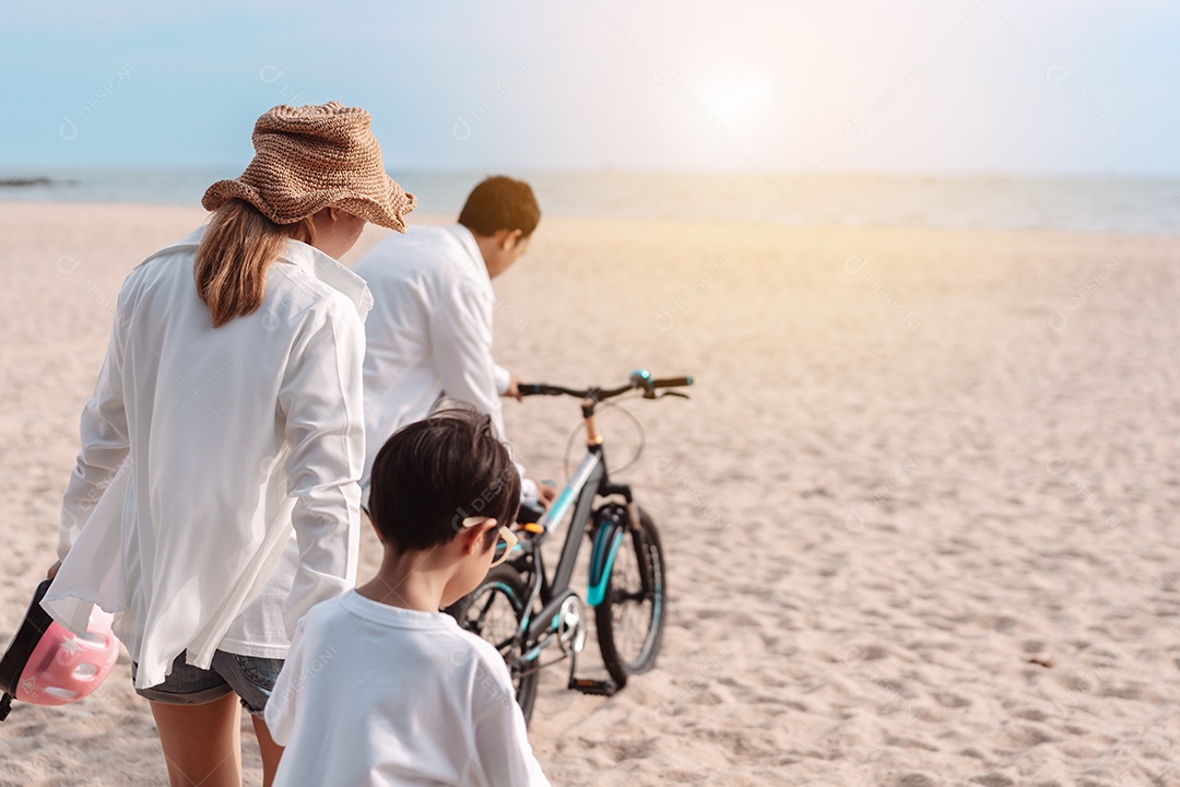 Família passeando pela praia ensinando filho a andar de bicicleta