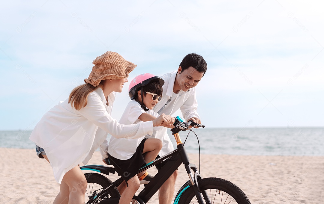 Família passeando pela praia ensinando filho a andar de bicicleta