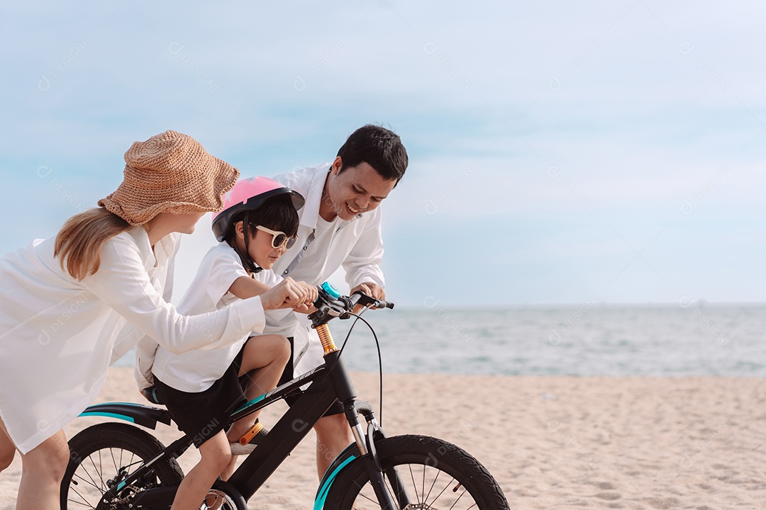 Família passeando pela praia ensinando filho a andar de bicicleta