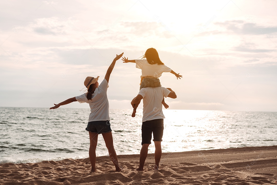 Linda família feliz brincando pela praia