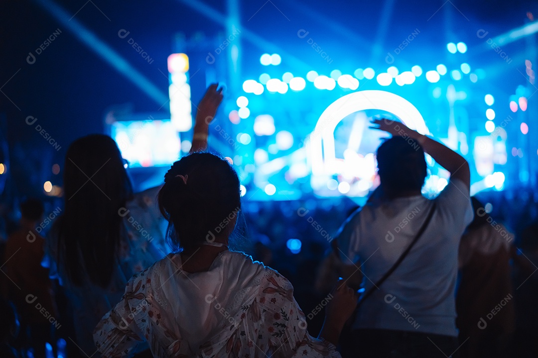 Multidão de mãos levantando as luzes do palco do concerto e a silhueta do público de fãs