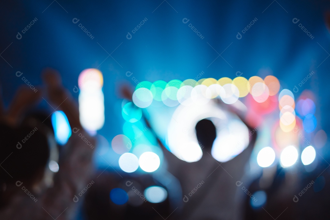 Multidão de mãos levantando as luzes do palco do concerto e a silhueta do público de fãs