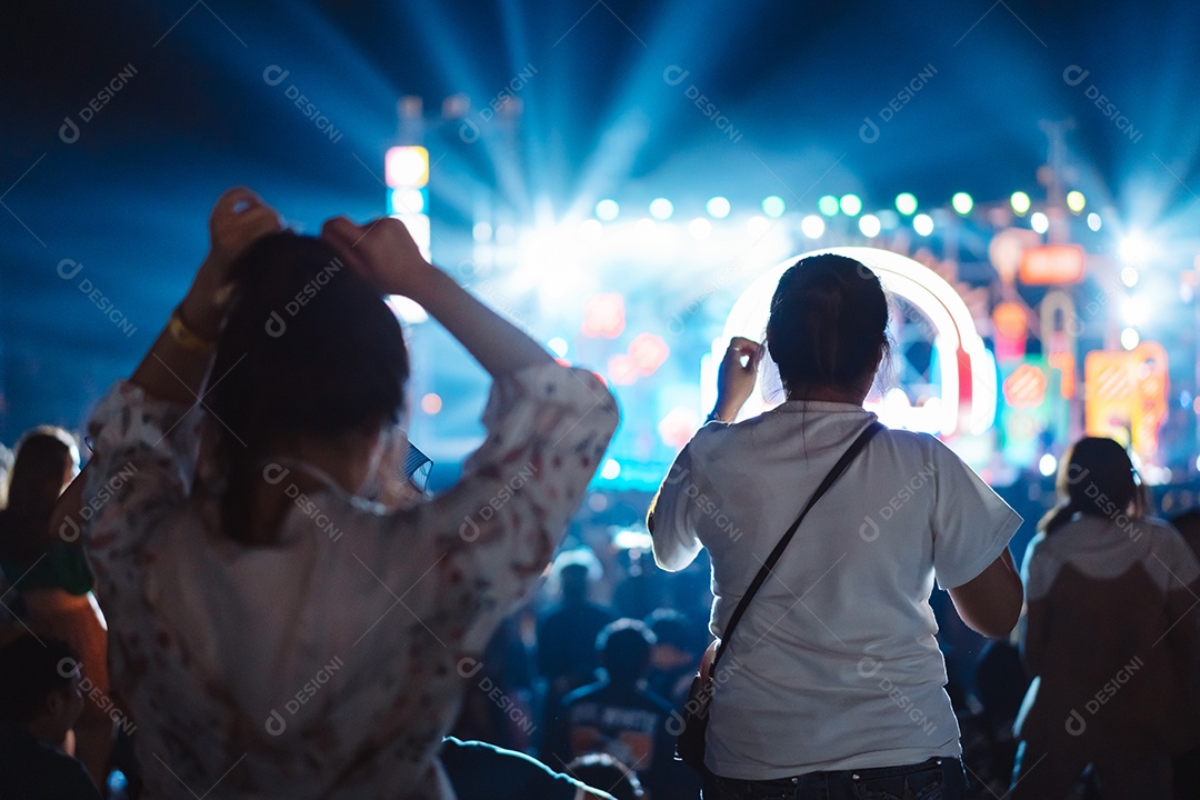 Multidão de mãos levantando as luzes do palco do concerto e a silhueta do público de fãs