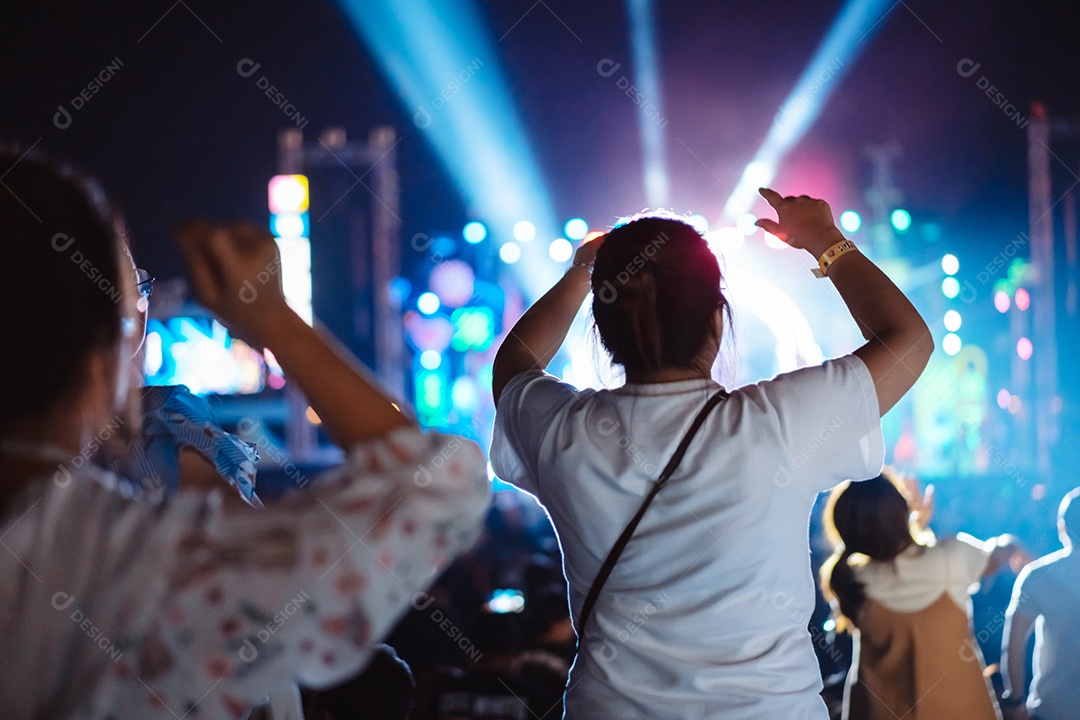 Multidão de mãos levantando as luzes do palco do concerto e a silhueta do público de fãs