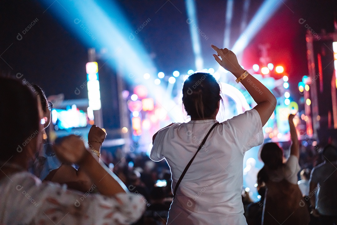 Multidão de mãos levantando as luzes do palco do concerto e a silhueta do público de fãs