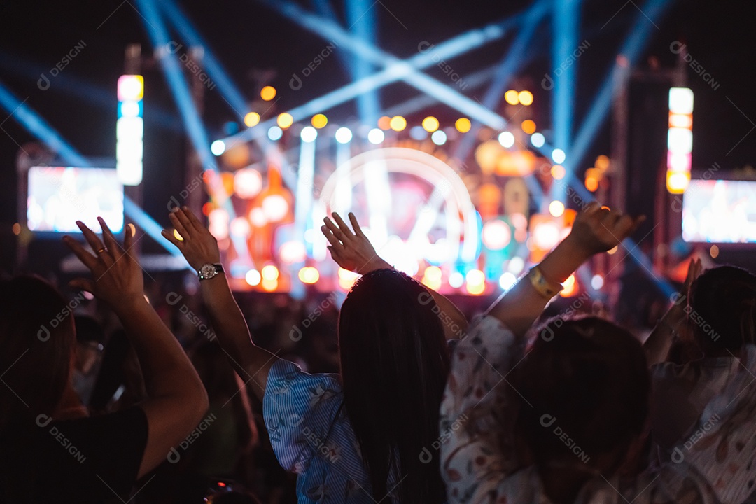 Multidão de mãos levantando as luzes do palco do concerto e a silhueta do público de fãs de pessoas
