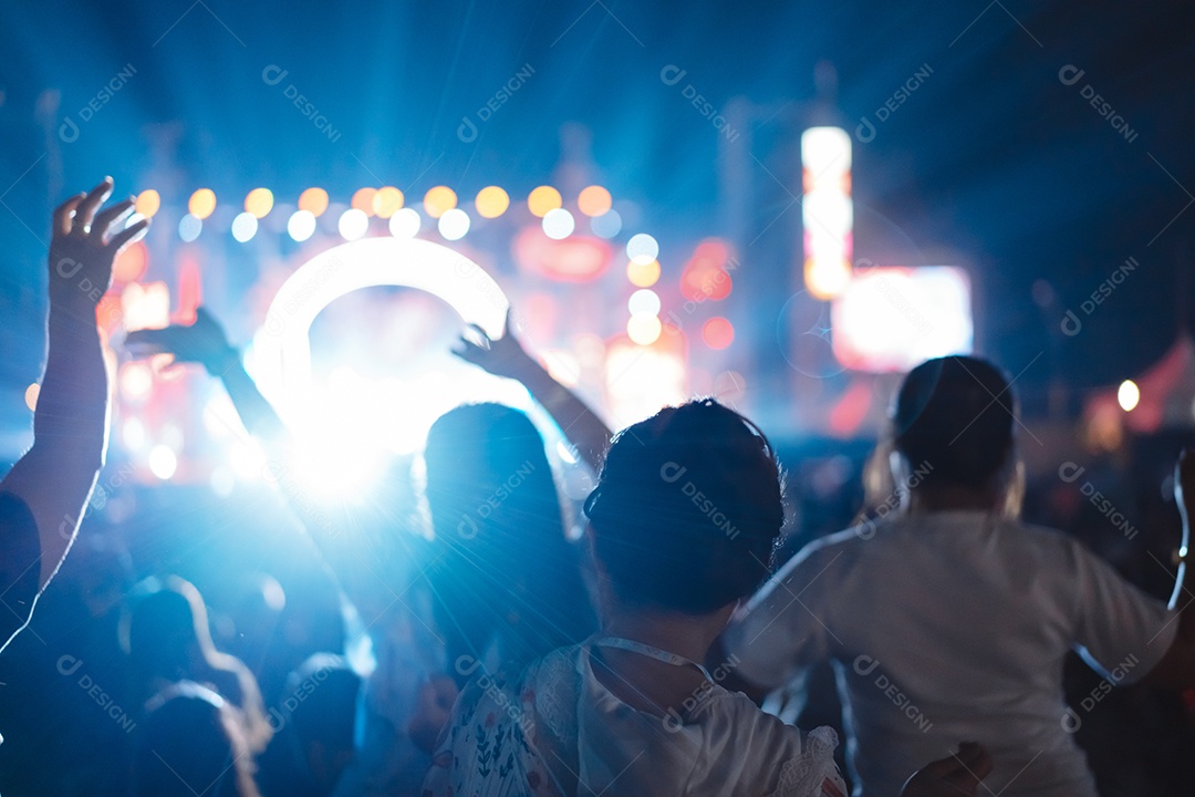 Multidão de mãos levantando as luzes do palco do concerto e a silhueta do público de fãs de pessoas