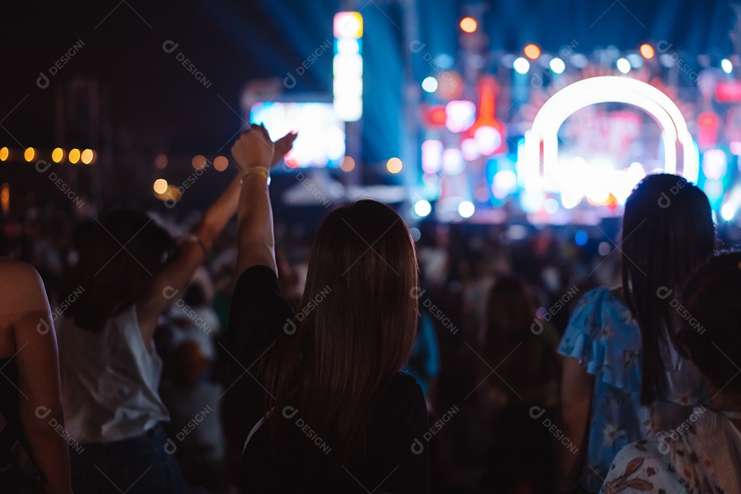 Multidão de mãos levantando as luzes do palco do concerto e a silhueta do público de fãs de pessoas