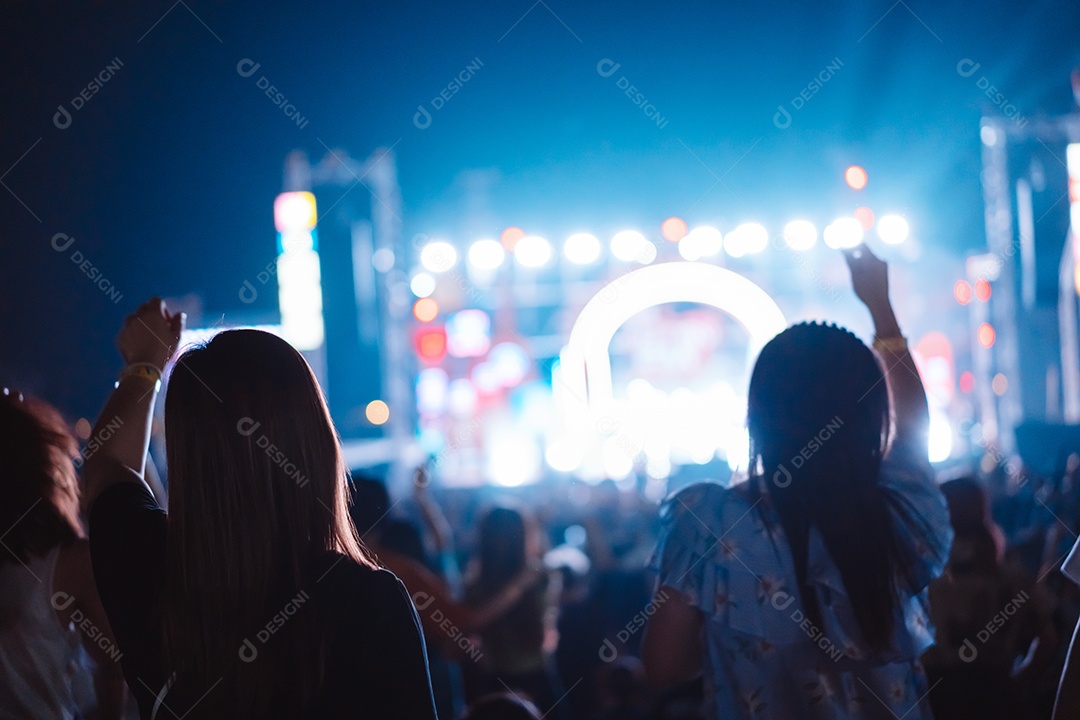 Multidão de mãos levantando as luzes do palco do concerto e a silhueta do público de fãs de pessoas