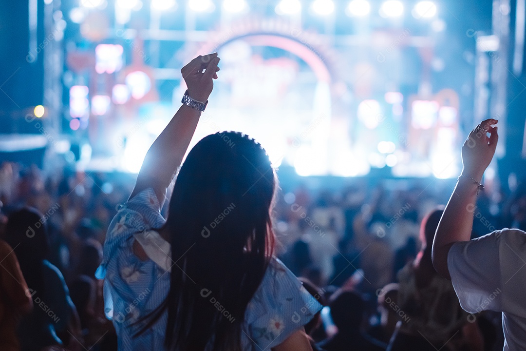 Multidão de mãos levantando as luzes do palco do concerto e a silhueta do público de fãs de pessoas