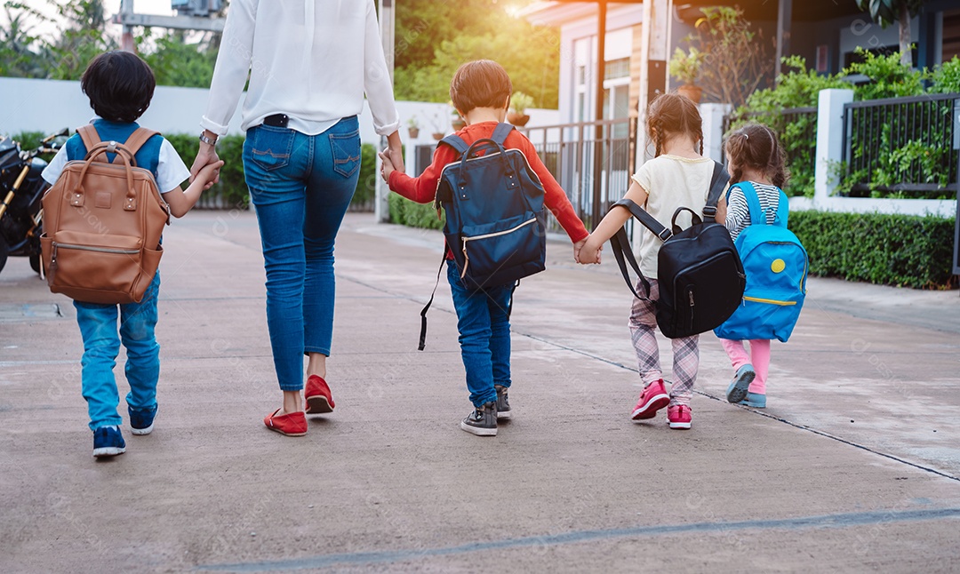 Mãe e aluno e filhos de mãos dadas indo para a escola na primeira classe com mochila