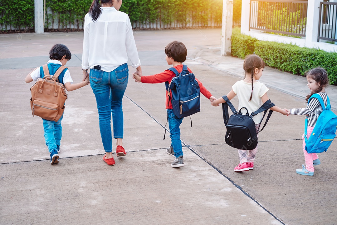 Mãe e aluno e filhos de mãos dadas indo para a escola na primeira classe com mochila
