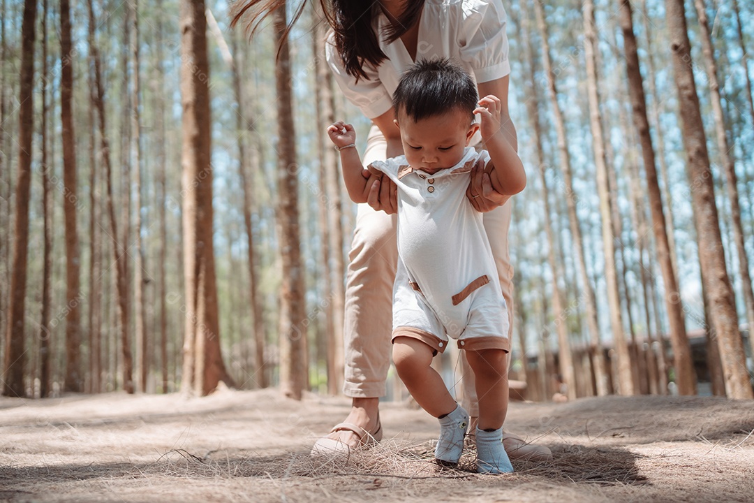 Bebê dando os primeiros passos na floresta na grama do prado.