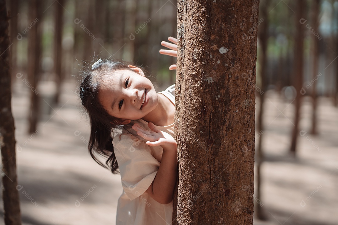 Menina brincando se escondendo atrás da árvore e acenando com a família