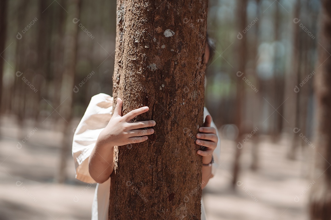 Menina brincando se escondendo atrás da árvore e acenando com a família