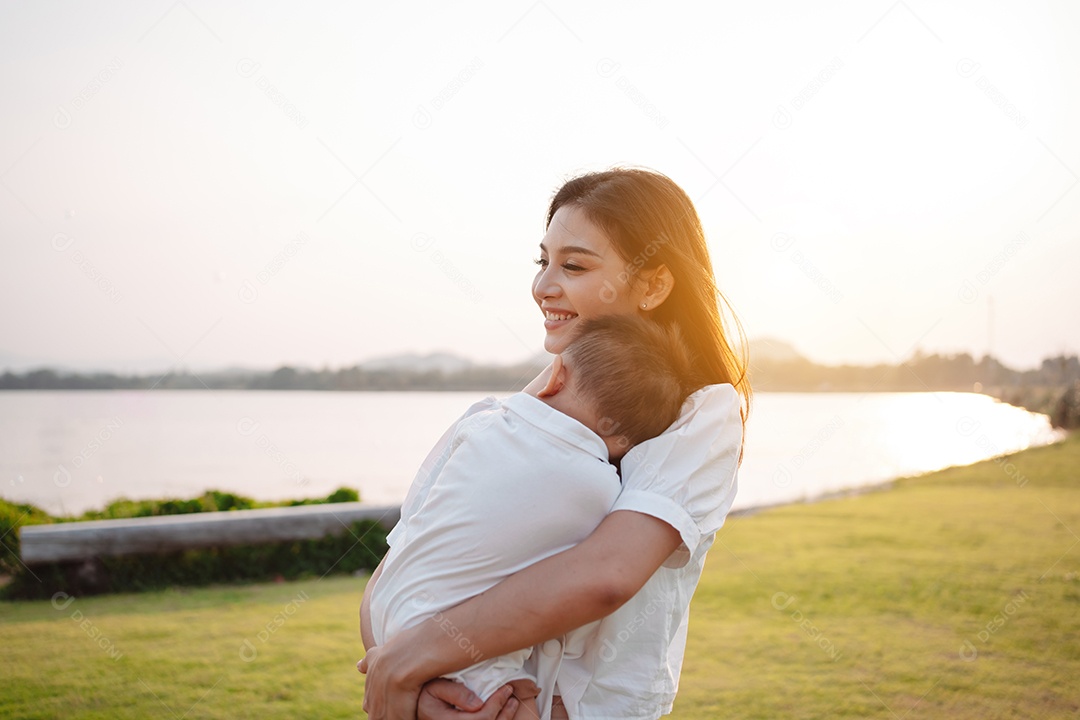 Mãe e filho juntos no pôr do sol do parque, família se divertindo juntos.