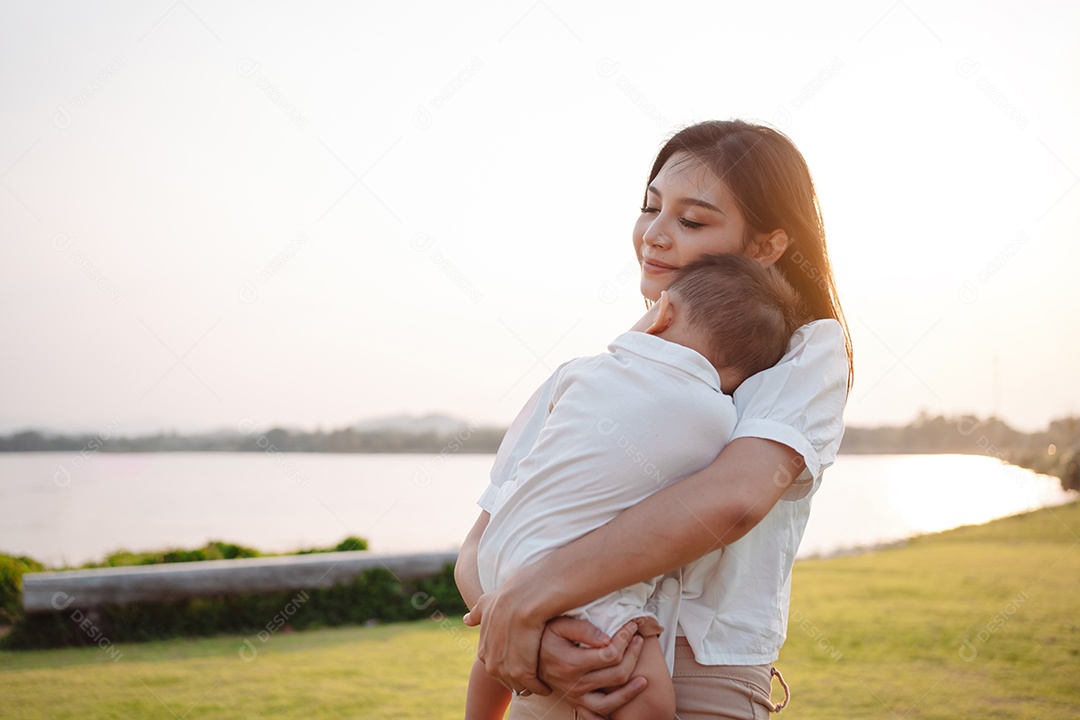 Mãe e filho juntos no pôr do sol do parque, família se divertindo juntos.