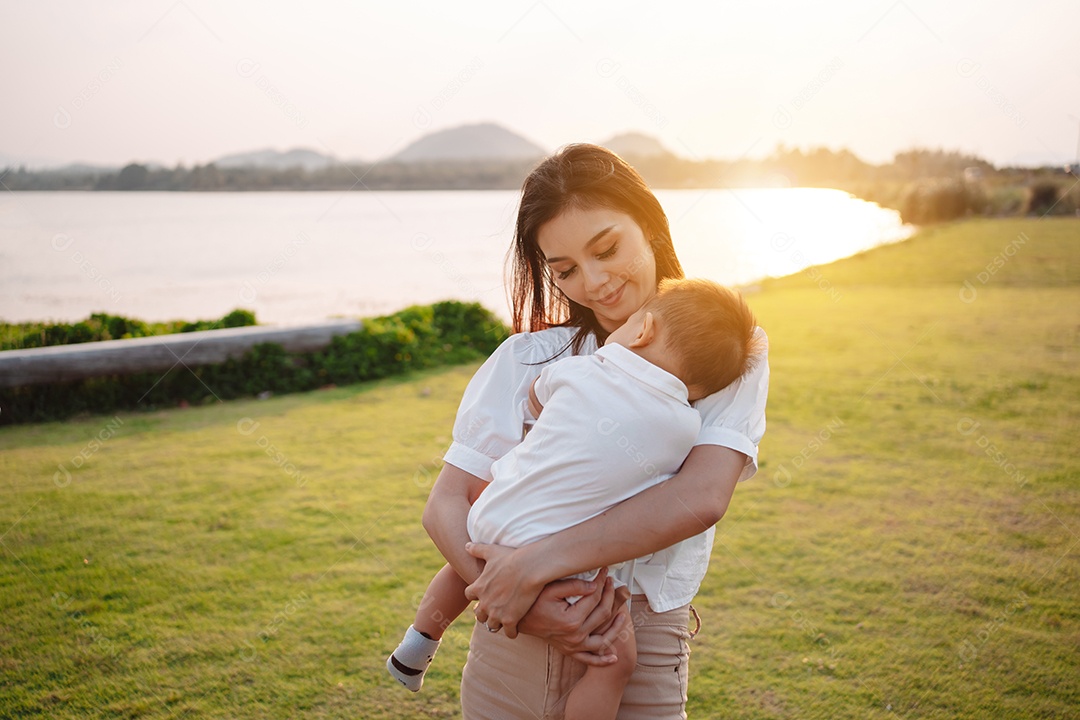 Mãe e filho juntos no pôr do sol do parque, família se divertindo juntos.