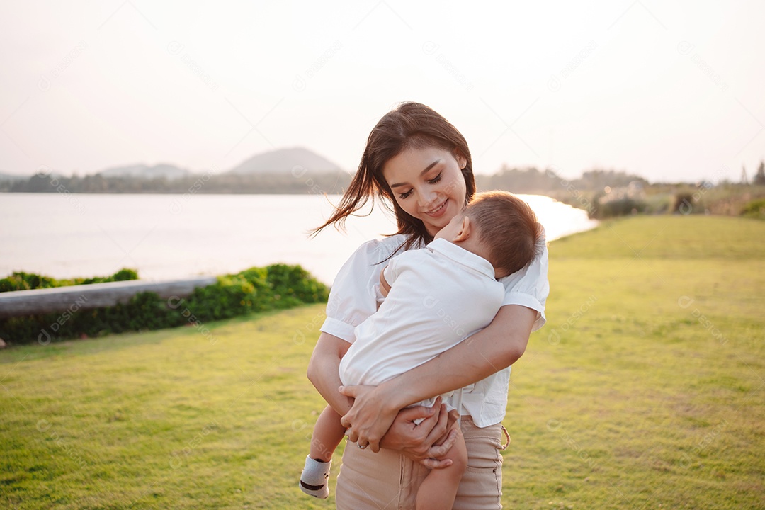 Mãe e filho juntos no pôr do sol do parque, família se divertindo juntos.