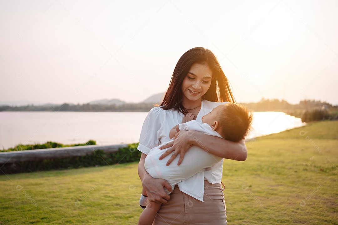 Mãe e filho juntos no pôr do sol do parque, família se divertindo juntos.