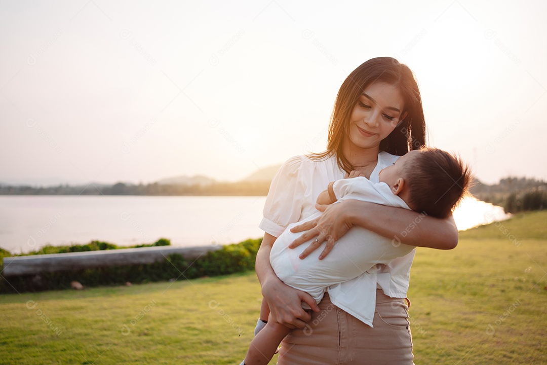 Mãe e filho juntos no pôr do sol do parque, família se divertindo juntos.